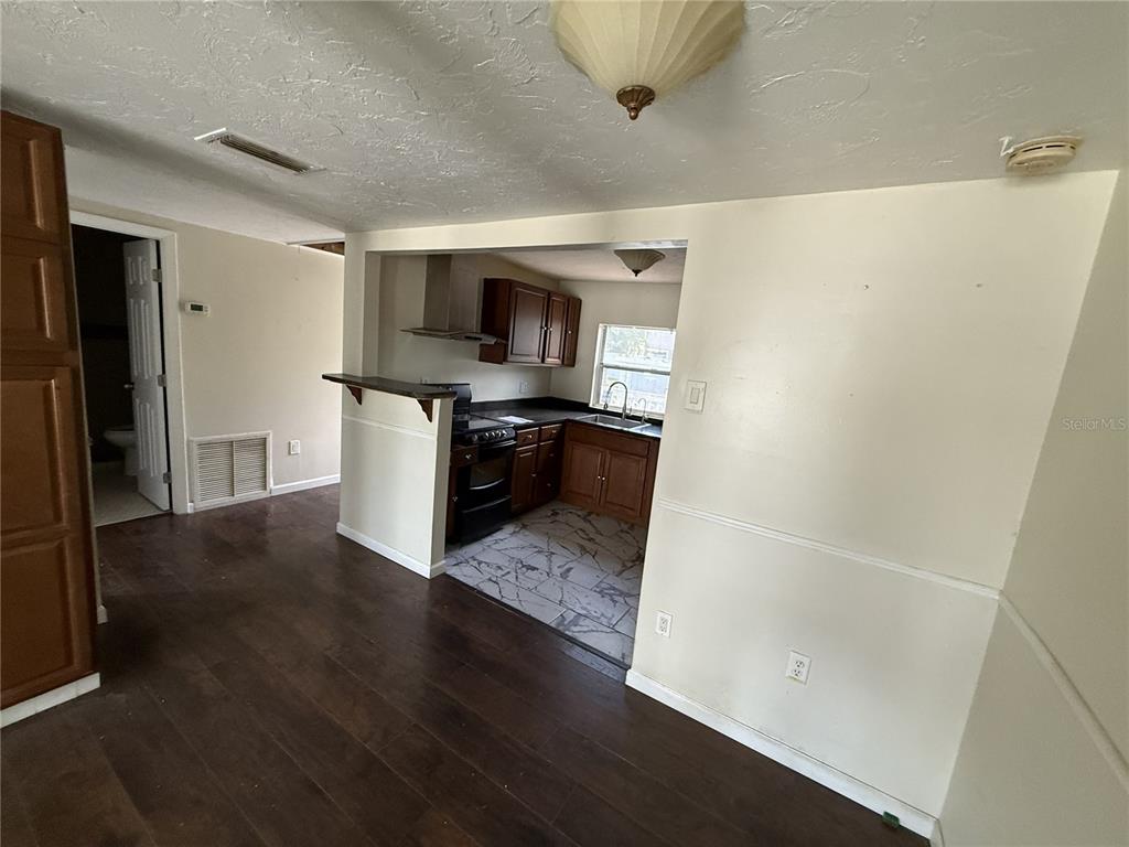 A kitchen with dark wood cabinets and a breakfast bar opens into a living area — 1810 9TH STREET W, PALMETTO, FL