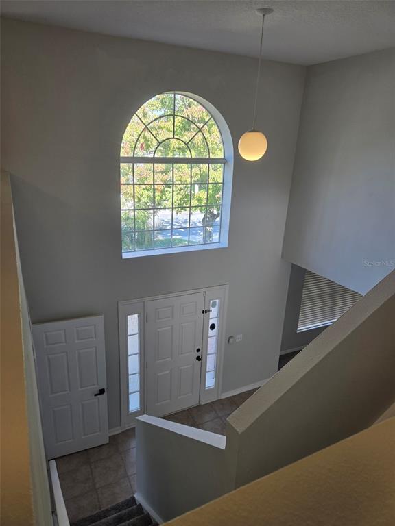 An elevated view of a foyer with a tall arched window, white door, and pendant light — 3001 MANDOLIN DRIVE, KISSIMMEE, FL