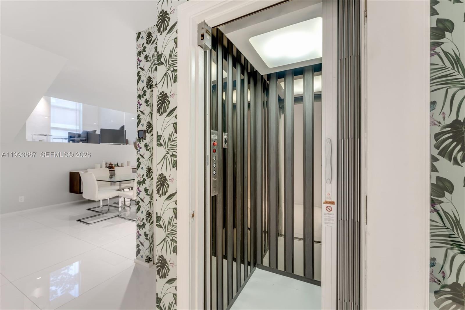 A residential elevator with a metal gate is positioned next to a dining area — 1524 NE Quayside Ter # A4, Miami FL 33138, MIAMI, FL
