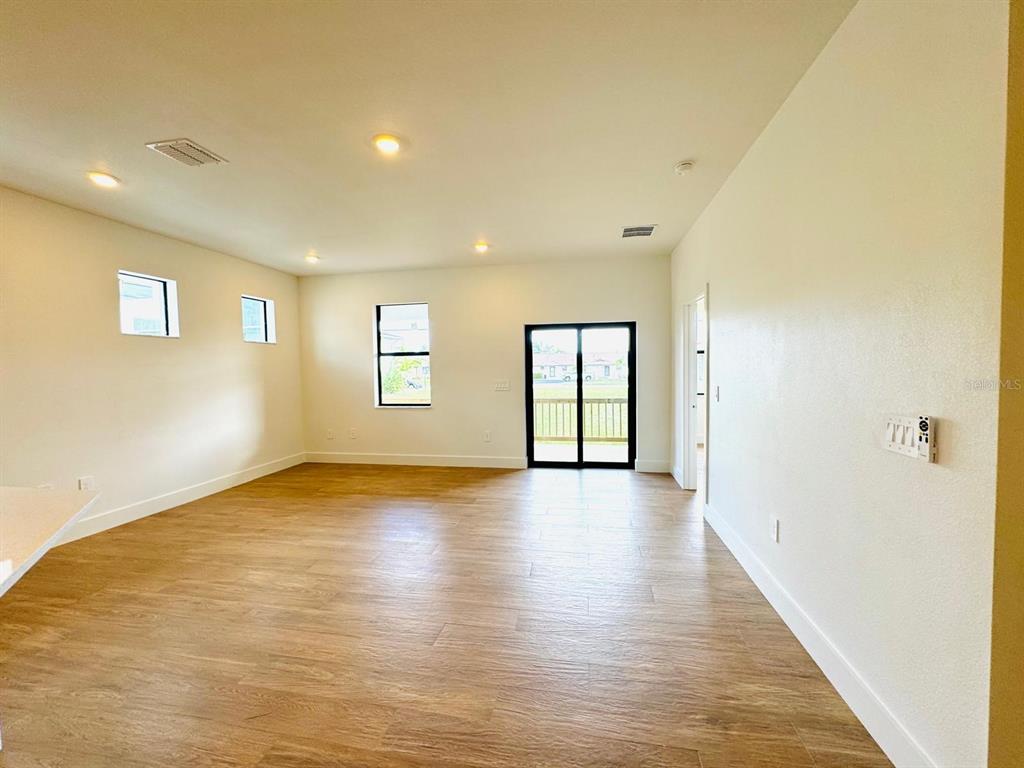 An empty room with light-colored walls, wood-look flooring, recessed lighting, and a sliding glass door — 1022 MARLIN DRIVE, PUNTA GORDA, FL
