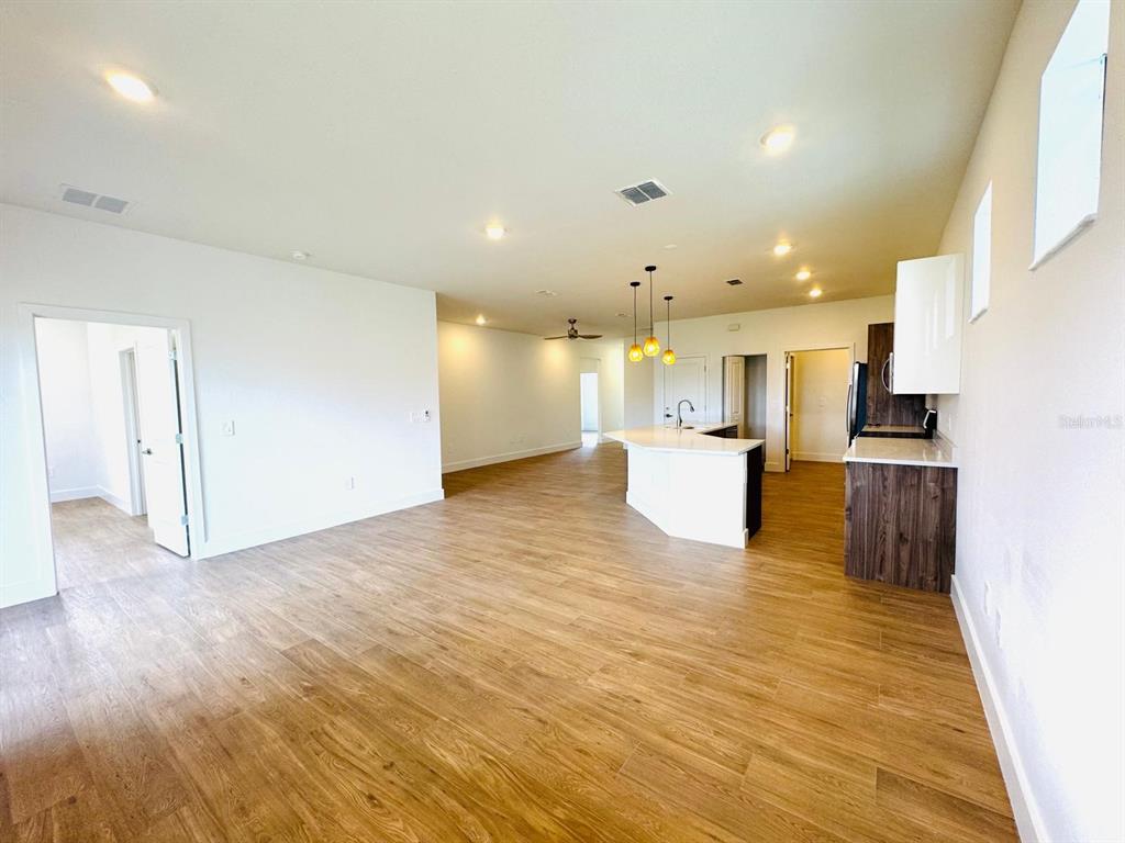 An open-concept living area features wood-look flooring, a kitchen island, and white cabinetry — 1022 MARLIN DRIVE, PUNTA GORDA, FL