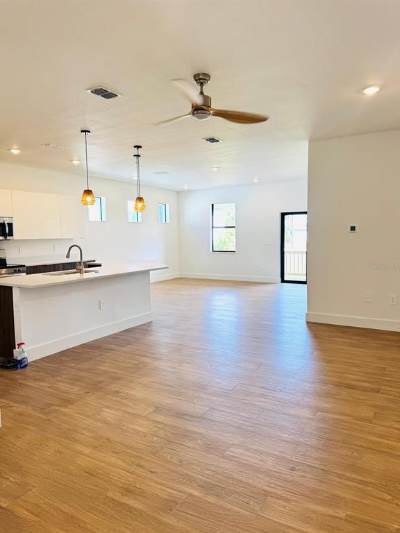 A modern kitchen with a white island and wood-look tile flooring opens to a living area — 1022 MARLIN DRIVE, PUNTA GORDA, FL