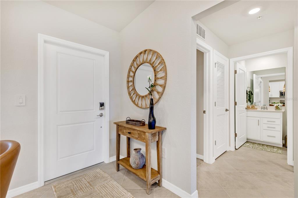 An entryway features a wooden console table, a round mirror, and a tiled floor — 17440 OPAL SAND DRIVE UNIT 202, VENICE, FL