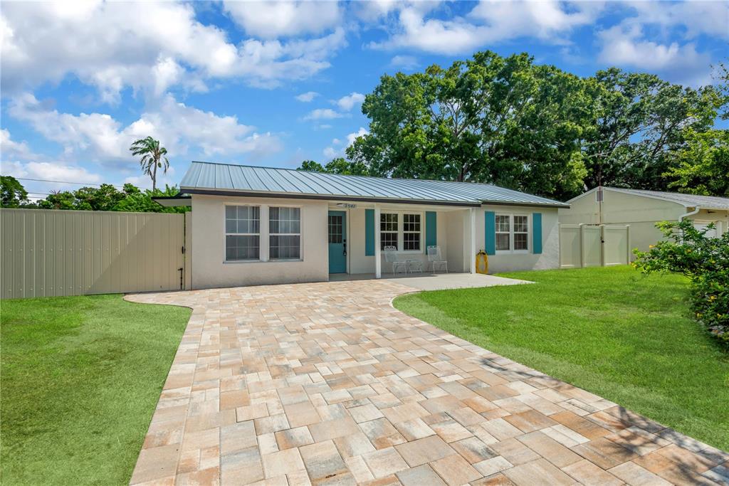 A single-story house with a metal roof, teal shutters, and a paved stone driveway — 2541 47TH AVENUE N, ST PETERSBURG, FL