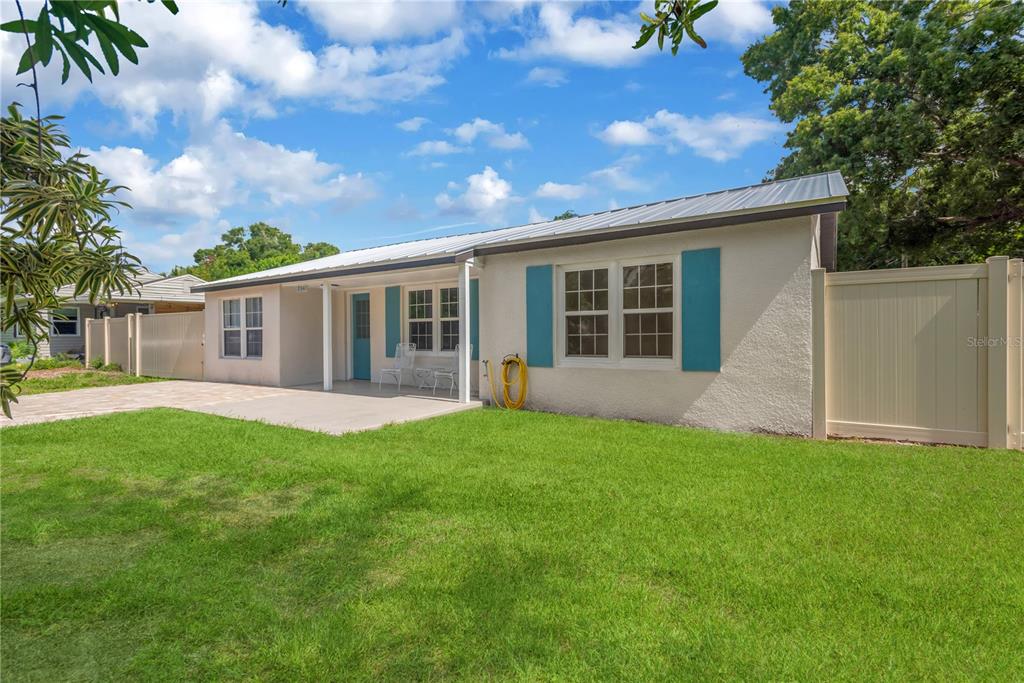 A single-story house with a metal roof, light stucco walls, and blue shutters — 2541 47TH AVENUE N, ST PETERSBURG, FL