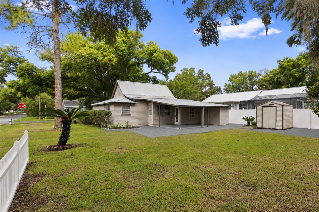 A single-story house with a metal roof, covered patio, and a shed in the yard — 5450 10TH STREET, ZEPHYRHILLS, FL