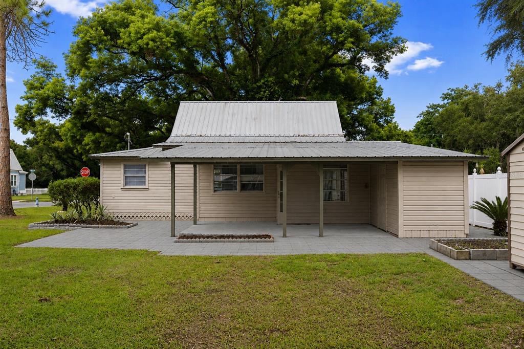 A single-story house with light-colored siding, a metal roof, and a covered front patio — 5450 10TH STREET, ZEPHYRHILLS, FL