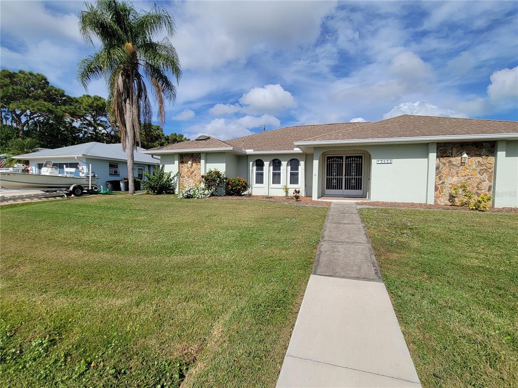 A single-story house with a light green exterior, stone accents, and a concrete walkway — 9400 NEW MARTINSVILLE AVENUE, ENGLEWOOD, FL