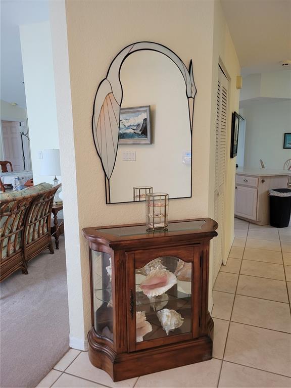 A wooden display cabinet with seashells sits below a decorative heron-shaped mirror in a hallway — 9400 NEW MARTINSVILLE AVENUE, ENGLEWOOD, FL