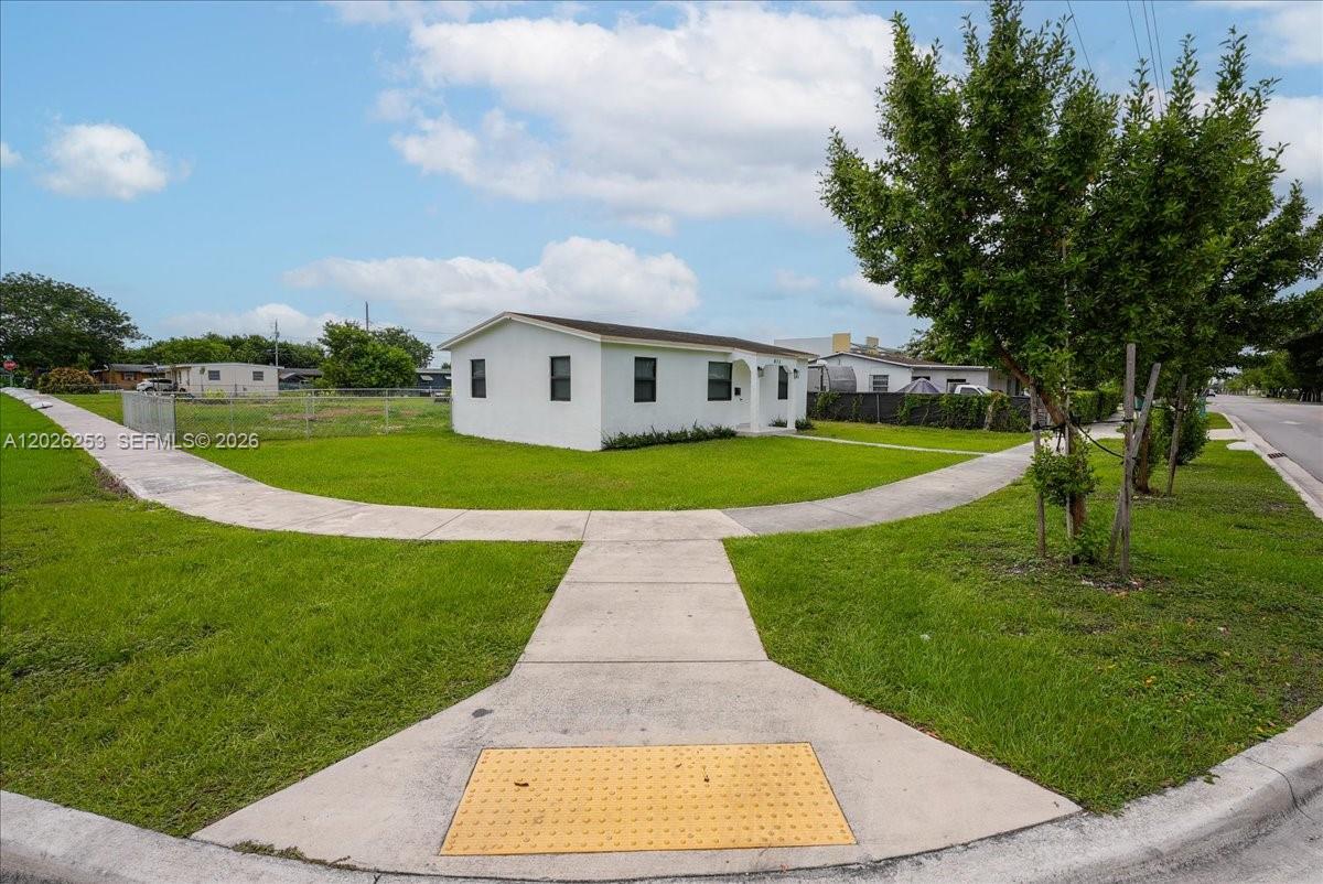 A white, single-story house sits on a corner lot with a sidewalk in the foreground — 813 NW 6th Ave, Florida City FL 33034, FLORIDA CITY, FL