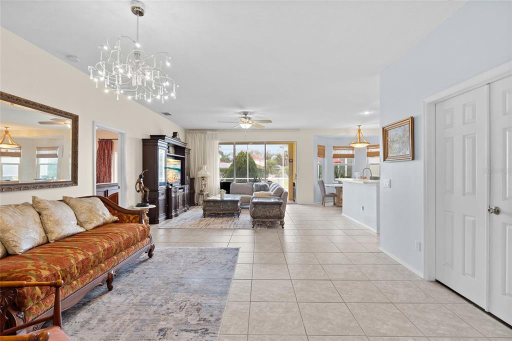 A spacious living room features tile flooring, a crystal chandelier, and a view of the patio — 4805 50TH AVENUE W, BRADENTON, FL