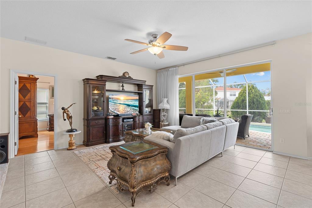 A living room features tile floors, a large sectional sofa, a media center, and sliding doors — 4805 50TH AVENUE W, BRADENTON, FL