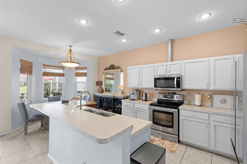 A kitchen with white cabinets, stainless steel appliances, a center island, and an adjacent dining area — 4805 50TH AVENUE W, BRADENTON, FL