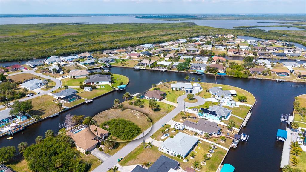 An aerial view shows a vacant, circular-highlighted residential lot situated along a canal in Florida — 17117 CANARY LANE, PORT CHARLOTTE, FL
