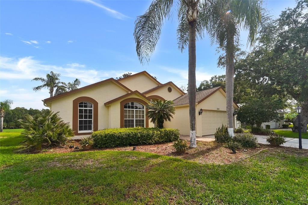 A single-story house with a beige stucco exterior, arched windows, and a two-car garage — 6541 COUNTRY RIDGE LANE, NEW PORT RICHEY, FL