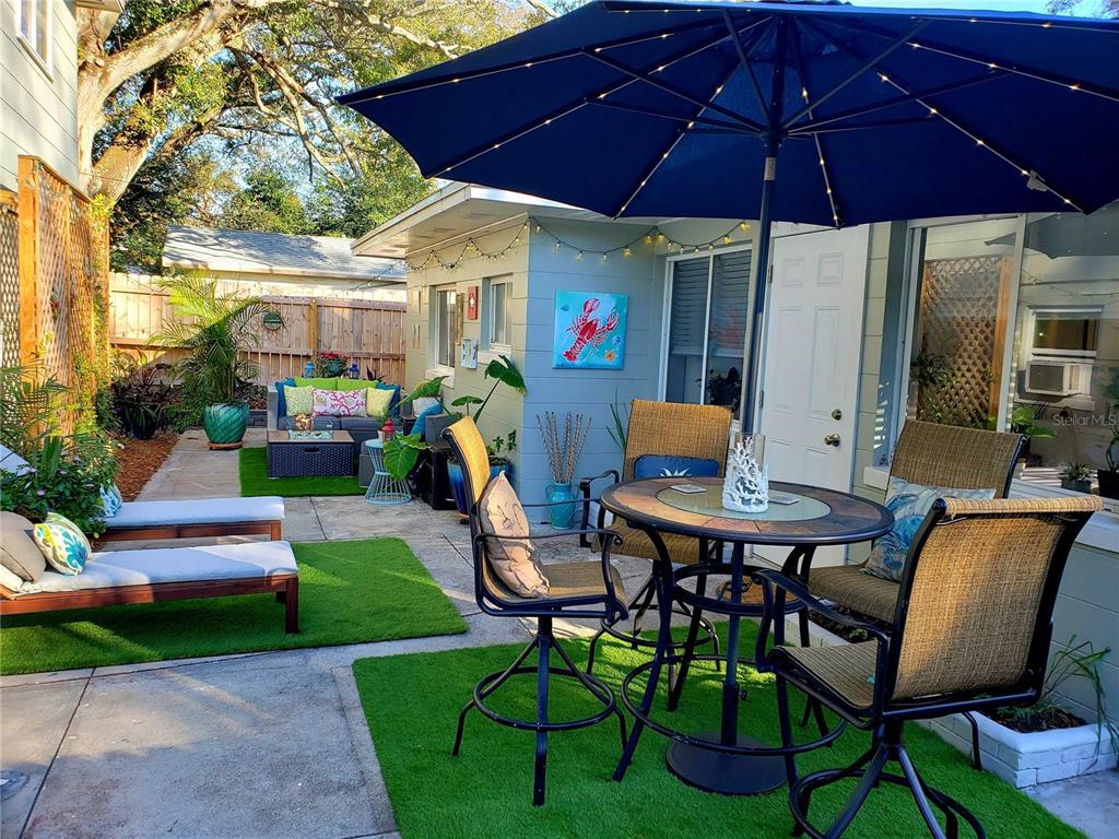 A patio features a dining set under a blue umbrella, lounge chairs, and artificial turf — 2035 28TH AVENUE N, ST PETERSBURG, FL