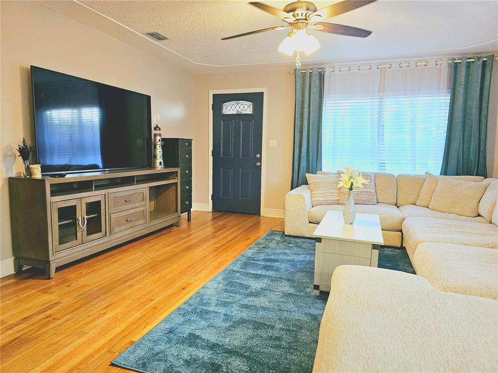A living room features hardwood floors, a large sectional sofa, a television console, and a door — 2035 28TH AVENUE N, ST PETERSBURG, FL