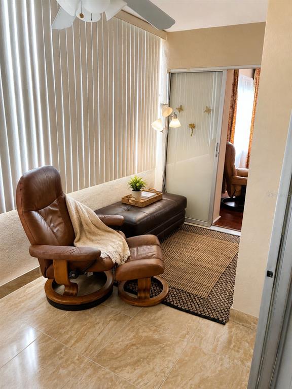 A sunroom features a leather recliner, a matching ottoman, a bench, and tile flooring — 4575 COVE CIRCLE UNIT 506, ST PETERSBURG, FL