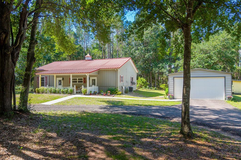 A single-story house with a red metal roof and a detached two-car garage — 14590 NE 35TH AVENUE, CHIEFLAND, FL