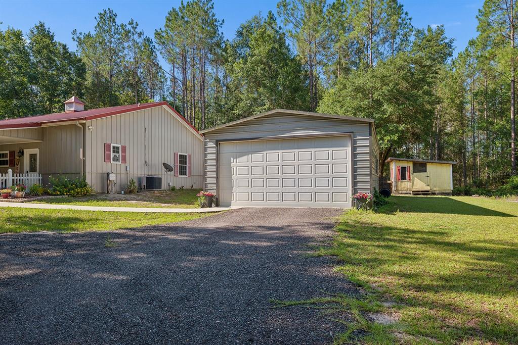 A house with a red roof, a detached garage, and a small shed in a yard — 14590 NE 35TH AVENUE, CHIEFLAND, FL