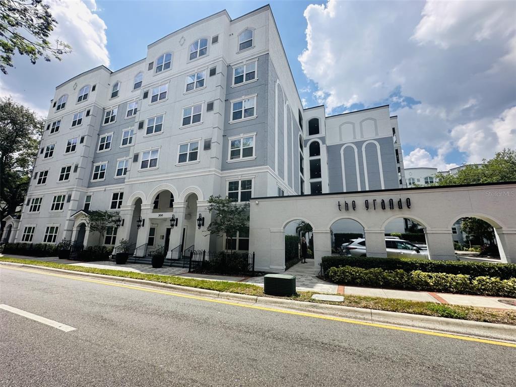 A multi-story apartment building with a light-colored facade and a gated entrance labeled The Grande — 204 E SOUTH STREET UNIT 3059, ORLANDO, FL