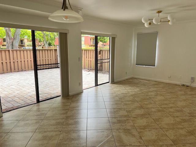 A bright room with tan tile flooring, two sliding glass doors, and two modern light fixtures — 8189 Thames Boulevard # D, Boca Raton FL 33433, BOCA RATON, FL