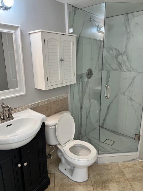 A bathroom features a white vanity, a toilet, and a glass-enclosed shower with marble-patterned tiles — 8189 Thames Boulevard # D, Boca Raton FL 33433, BOCA RATON, FL