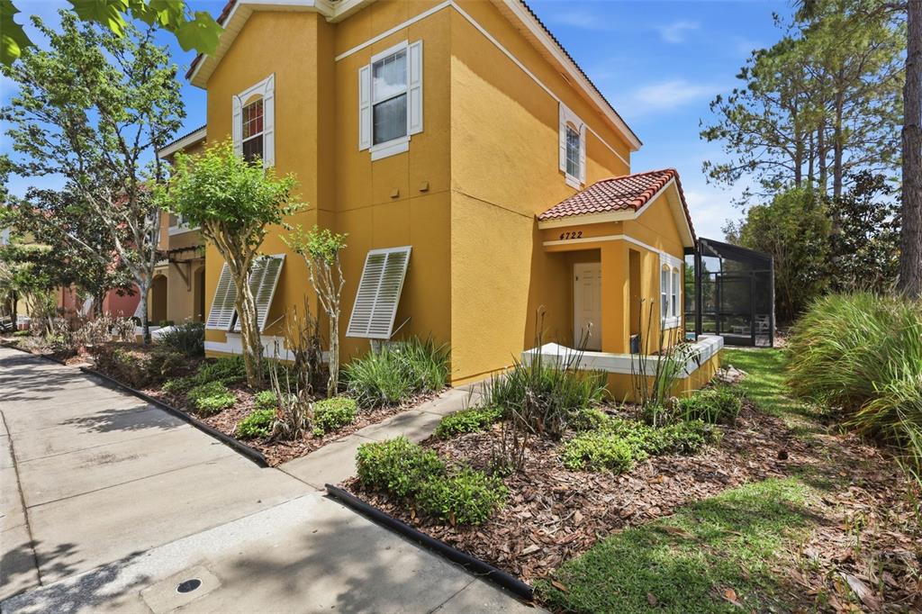 A two-story yellow stucco townhouse with a tiled entryway and a screened-in back patio — 4722 ORMOND BEACH WAY, KISSIMMEE, FL