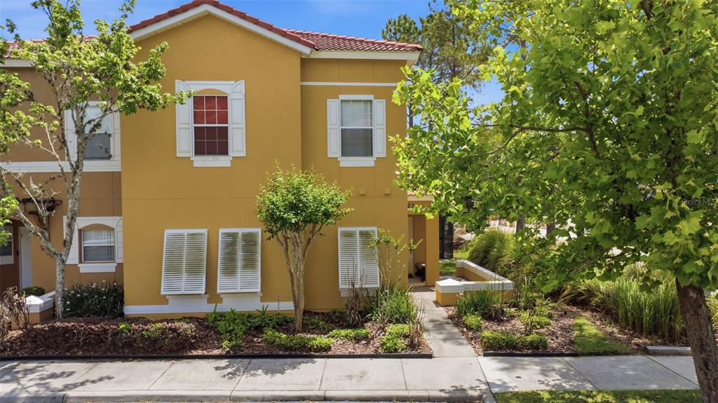 A two-story yellow stucco townhouse with white shutters and a tiled roof — 4722 ORMOND BEACH WAY, KISSIMMEE, FL