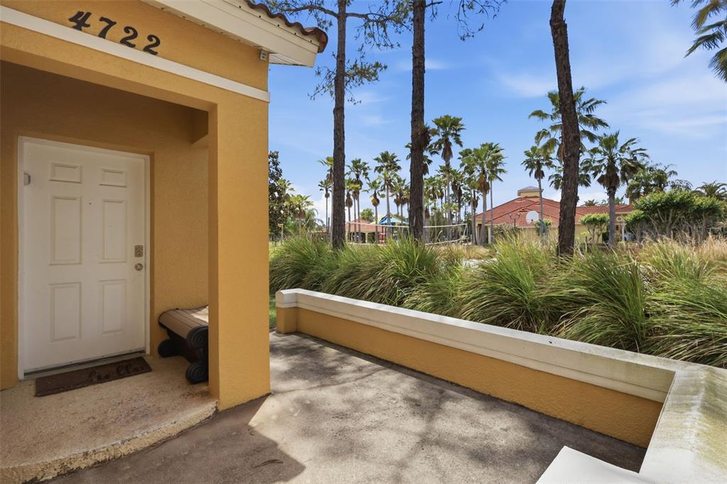 A covered entryway with a white door, a small bench, and a view of palm trees — 4722 ORMOND BEACH WAY, KISSIMMEE, FL