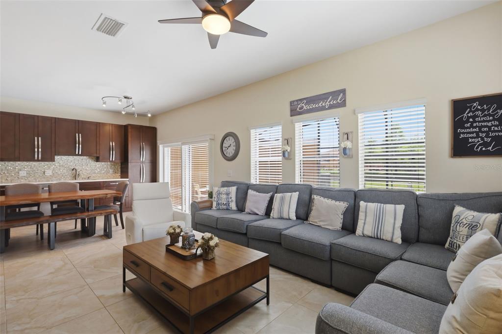 A living room features a large gray sectional sofa, a wooden coffee table, and an adjacent kitchen — 4722 ORMOND BEACH WAY, KISSIMMEE, FL