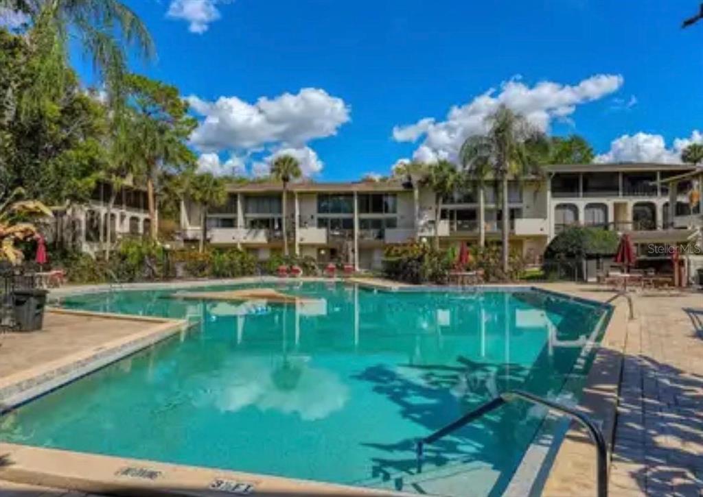 A swimming pool sits in front of a multi-story apartment building with palm trees — 200 MAITLAND AVENUE UNIT 34, ALTAMONTE SPRINGS, FL