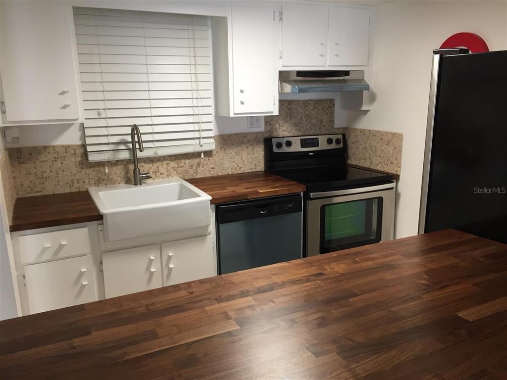 A kitchen features white cabinets, a farmhouse sink, wood countertops, and stainless steel appliances — 200 MAITLAND AVENUE UNIT 34, ALTAMONTE SPRINGS, FL