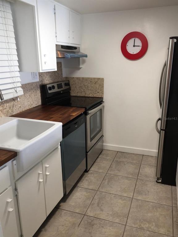 A kitchen features white cabinets, a farmhouse sink, wood countertops, and stainless steel appliances — 200 MAITLAND AVENUE UNIT 34, ALTAMONTE SPRINGS, FL