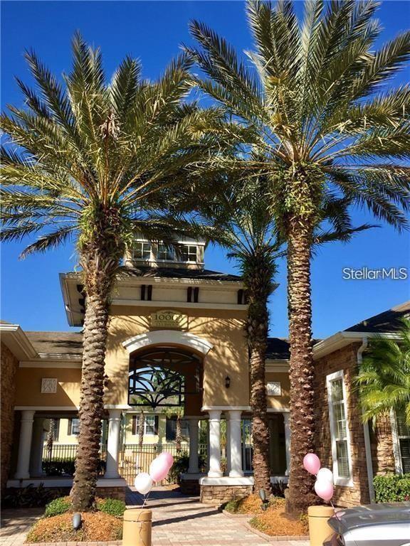 A tan building entrance features a central archway flanked by two tall palm trees — 10203 COURTNEY PALMS BOULEVARD UNIT 201, TAMPA, FL