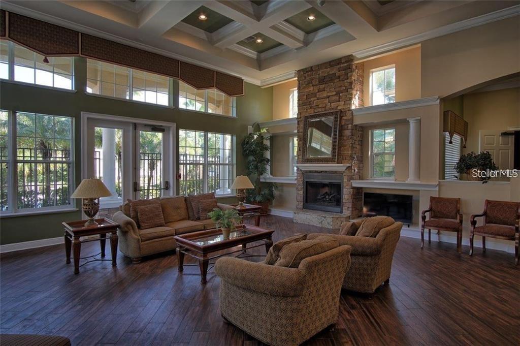 A spacious living room features a stone fireplace, coffered ceiling, and large windows with views — 10203 COURTNEY PALMS BOULEVARD UNIT 201, TAMPA, FL