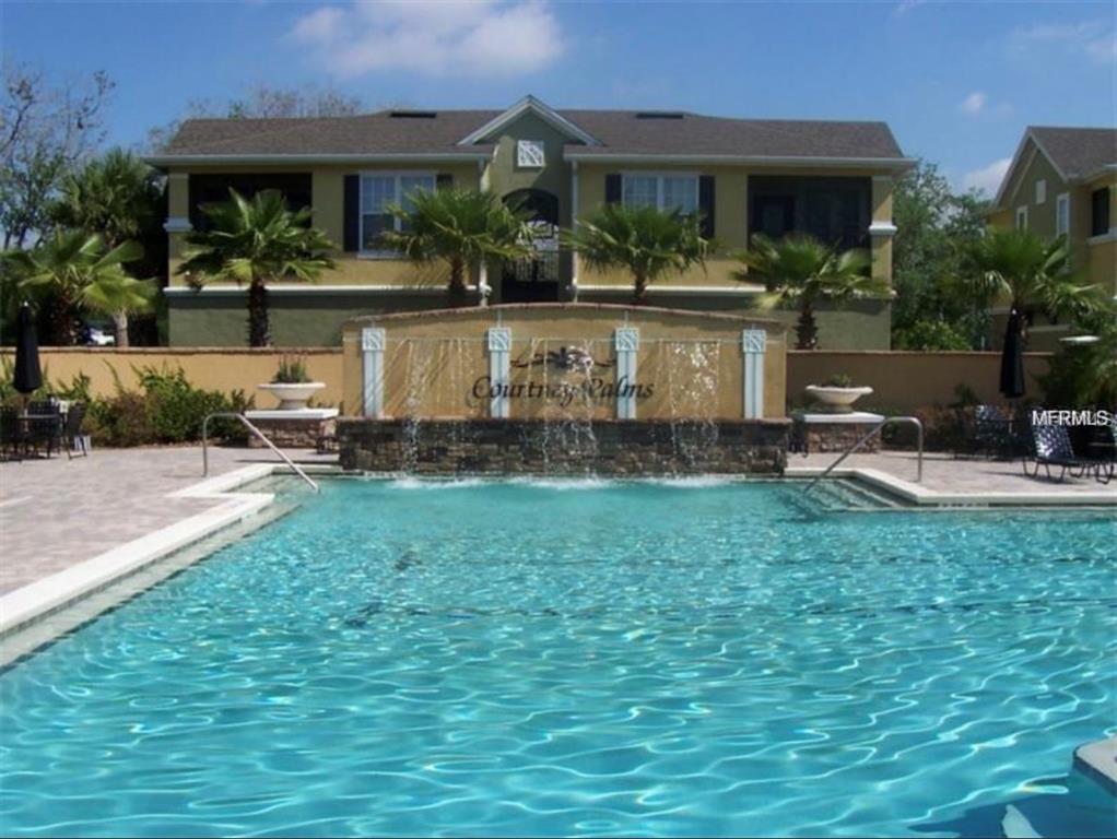 A swimming pool with a stone water feature sits in front of a residential building — 10203 COURTNEY PALMS BOULEVARD UNIT 201, TAMPA, FL