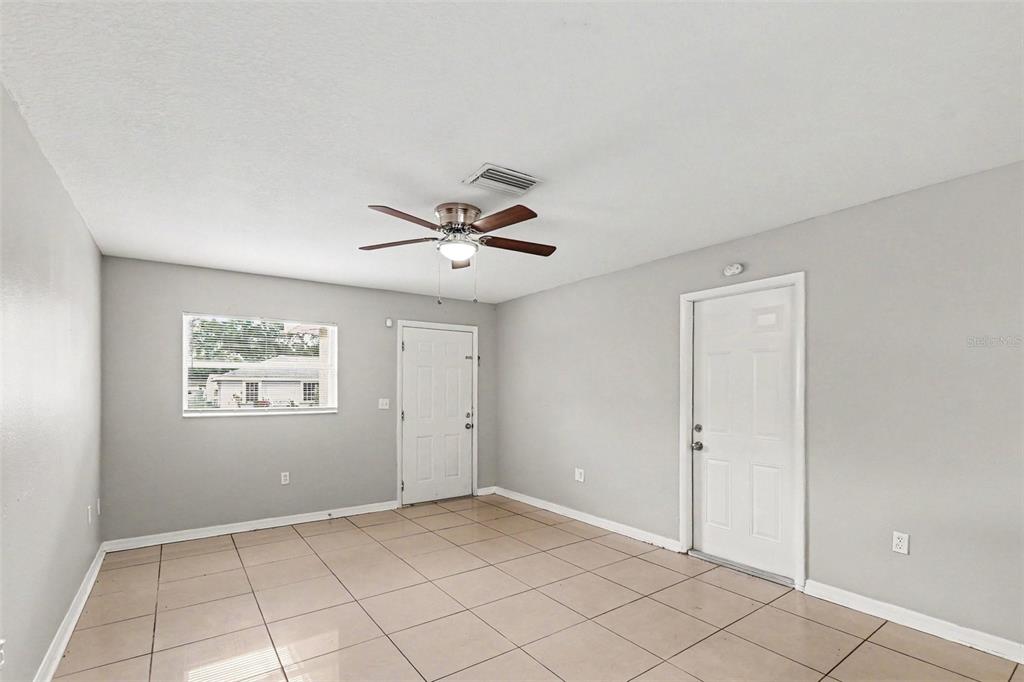 An empty room with light gray walls, tile flooring, a ceiling fan, and two doors — 2608 5TH AVENUE E, PALMETTO, FL