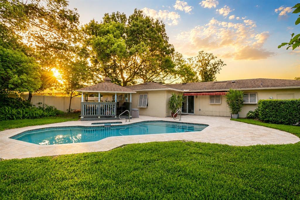 A backyard features a swimming pool, a gazebo, and a single-story house at sunset — 3736 LAKE MARGARET DRIVE, ORLANDO, FL