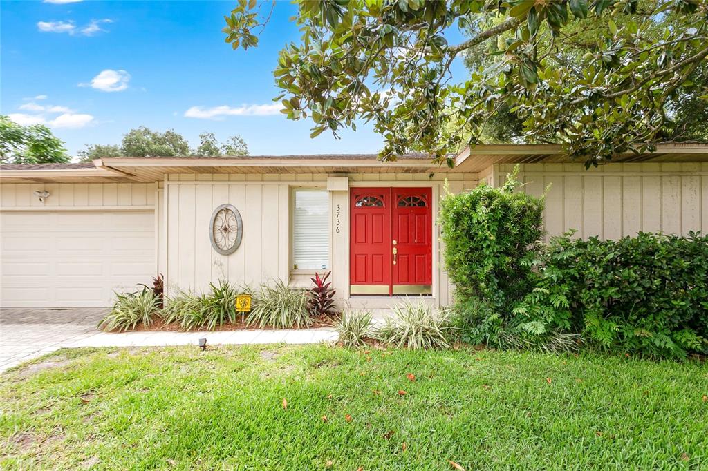 A single-story house features a red double front door, light-colored siding, and a garage — 3736 LAKE MARGARET DRIVE, ORLANDO, FL