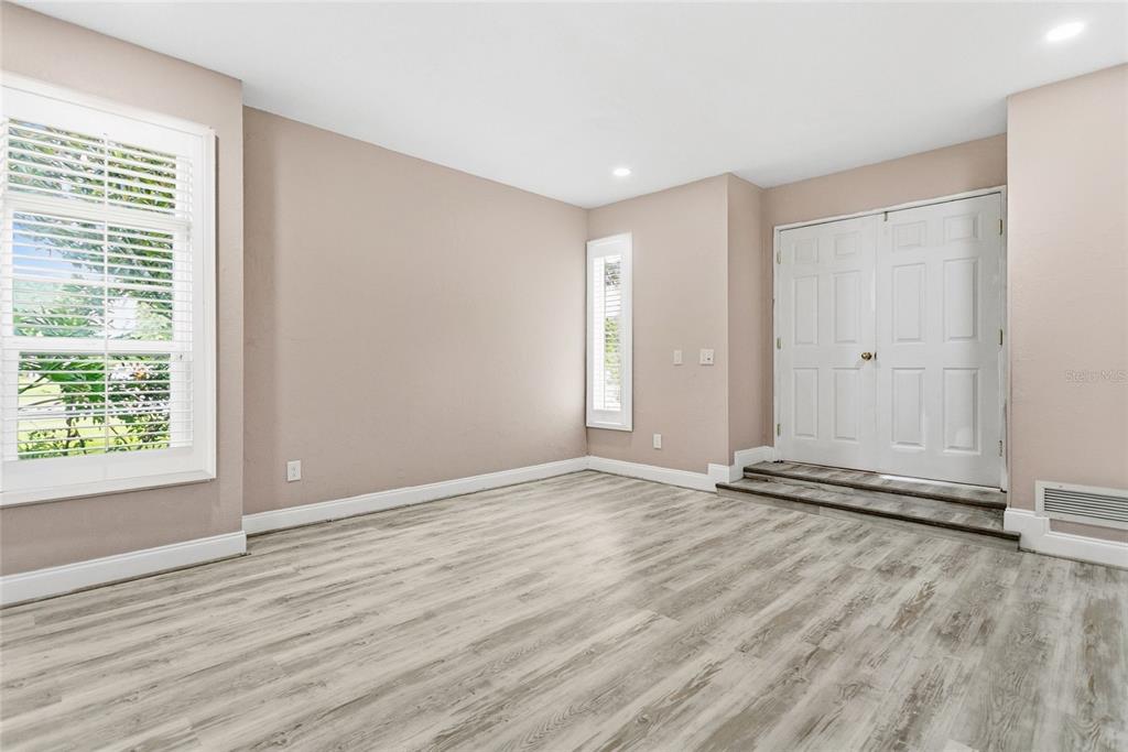 An empty room with light wood-look flooring, beige walls, a large window, and double doors — 3736 LAKE MARGARET DRIVE, ORLANDO, FL