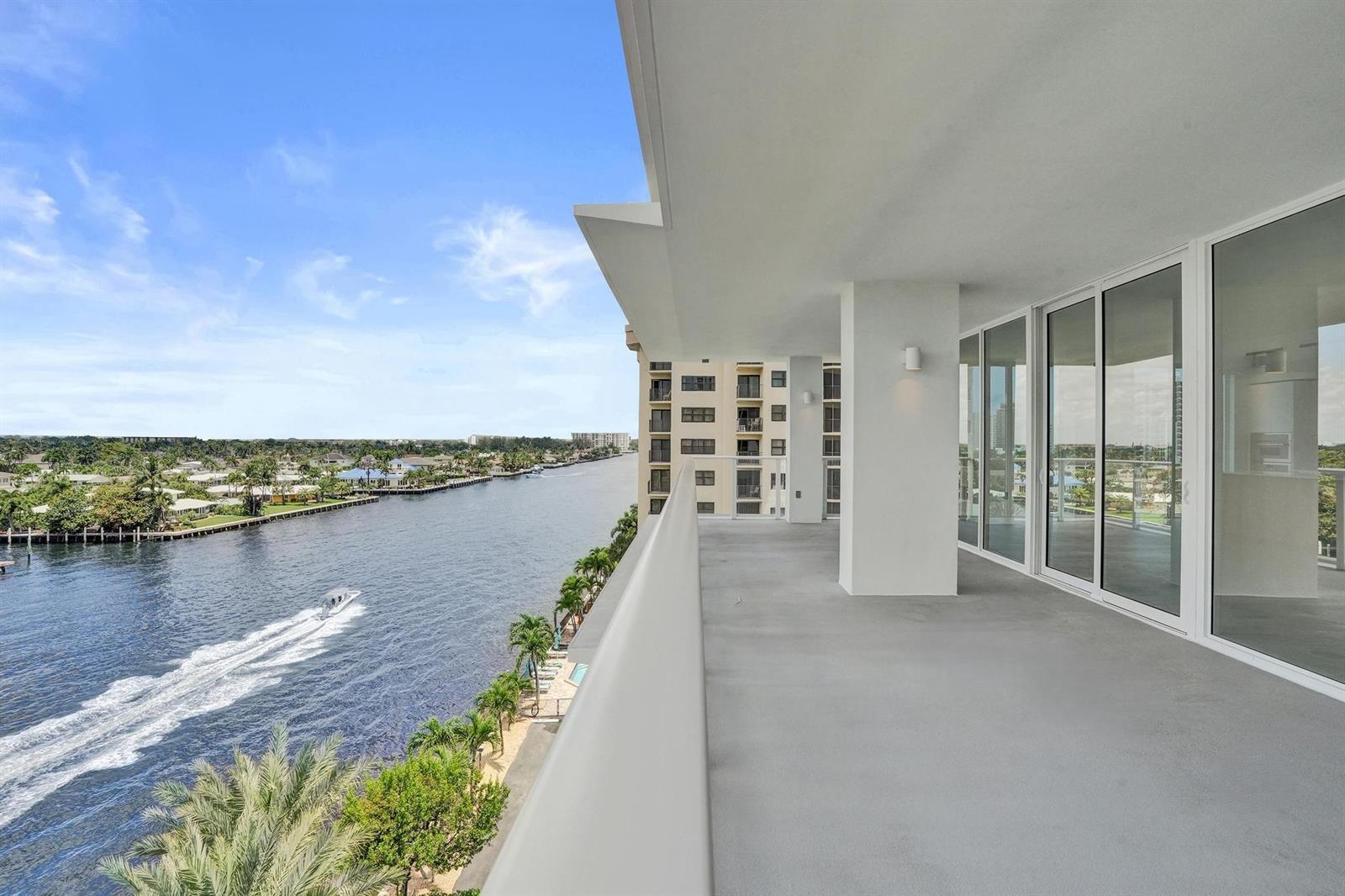 A spacious concrete balcony overlooks a wide river with a boat moving through the water — 407 N Riverside Drive # 605, Pompano Beach FL 33062, POMPANO BEACH, FL