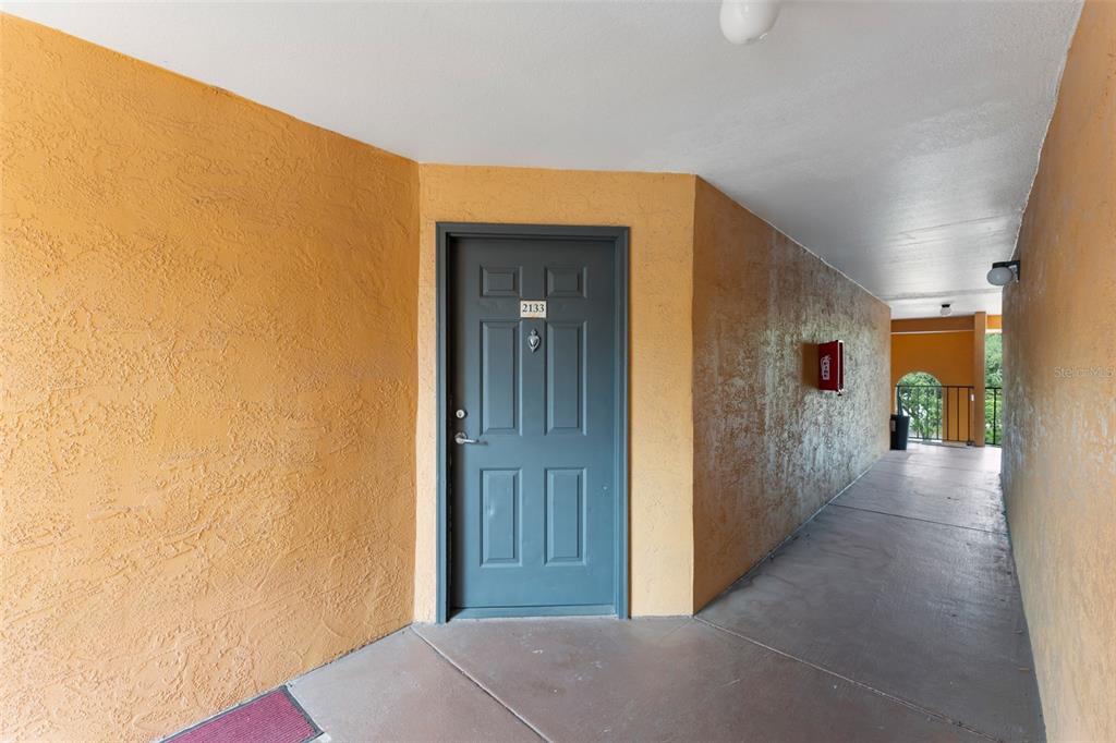 A gray apartment door with the number 2133 is set in a textured orange wall — 4532 COMMANDER DRIVE UNIT 2133, ORLANDO, FL