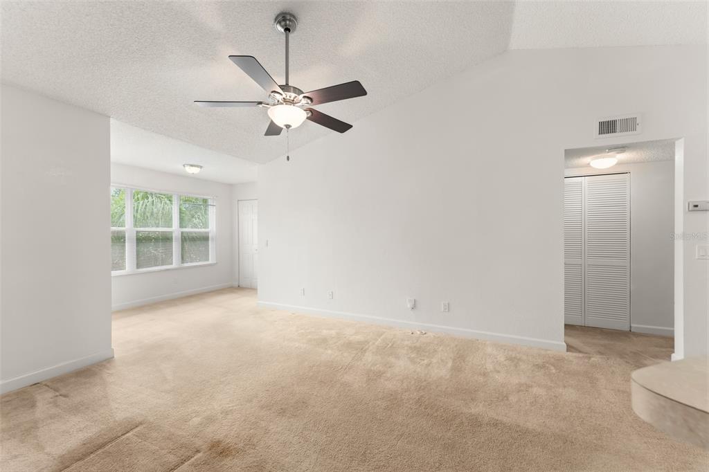 An empty living room features beige carpeting, white walls, and a ceiling fan — 4532 COMMANDER DRIVE UNIT 2133, ORLANDO, FL