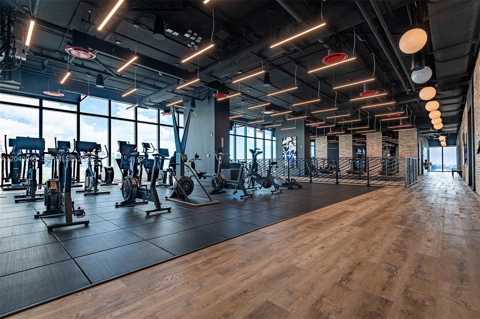 A modern gym features exercise equipment on black rubber mats and wood-look flooring — 398 NE 5th St # 2301, Miami FL 33132, MIAMI, FL
