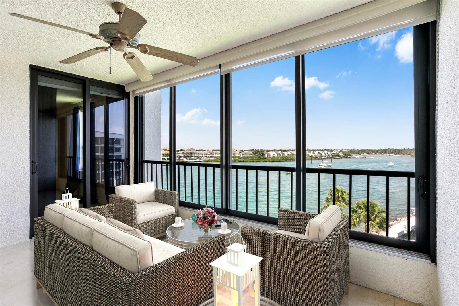 A balcony with wicker furniture, a ceiling fan, and large windows overlooking a waterfront view — 1748 Jupiter Cove Drive # 524a, Jupiter FL 33469, JUPITER, FL