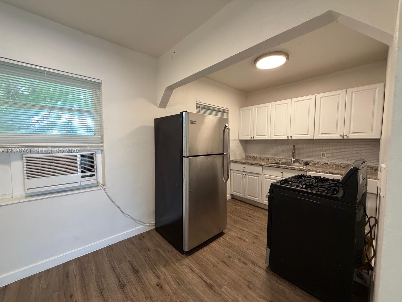 A kitchen features white cabinets, stainless steel appliances, a black stove, and wood-look flooring — 541 SW 7th St # 3, Miami FL 33130, MIAMI, FL