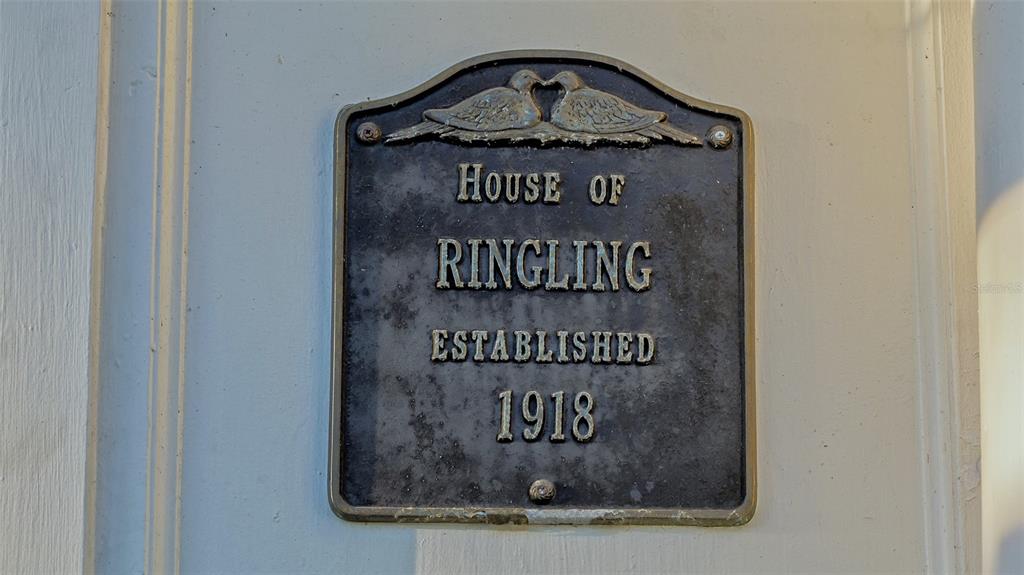 A metal plaque on a white wall reads House of Ringling Established 1918 — 7715 WESTMORELAND DRIVE, SARASOTA, FL