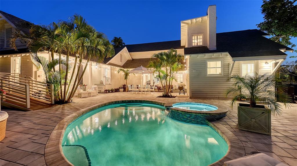 A backyard with a swimming pool, hot tub, patio, and palm trees at dusk — 7715 WESTMORELAND DRIVE, SARASOTA, FL