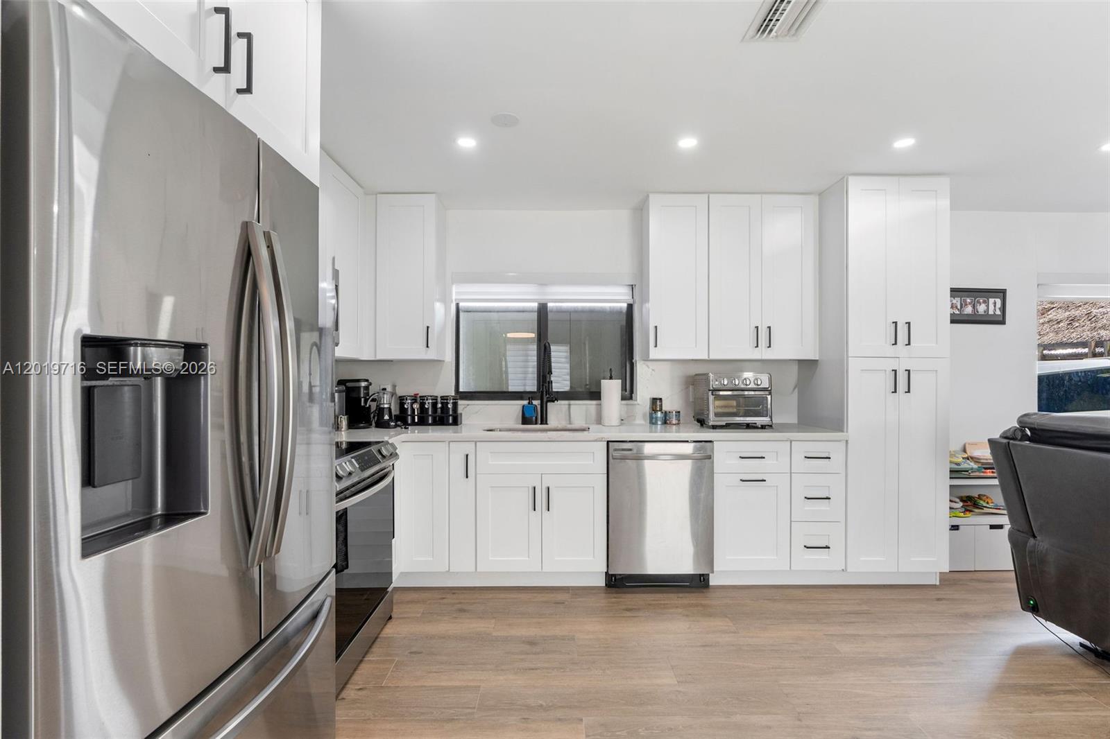 A modern kitchen features white cabinets, stainless steel appliances, and wood-look flooring — 9460 Haitian Dr, Cutler Bay FL 33189, CUTLER BAY, FL